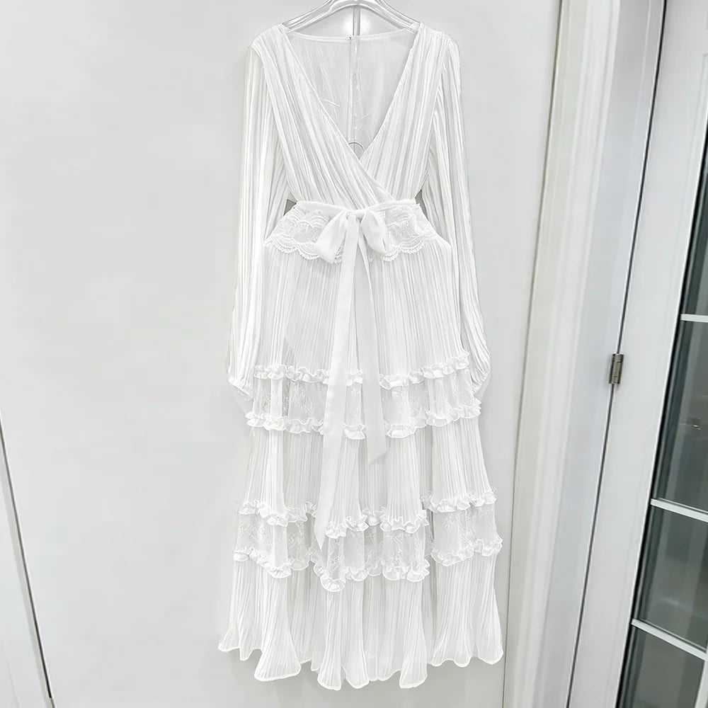White dress with ruffled layers on a hanger against a white wall.