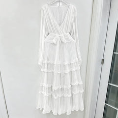 White dress with ruffled layers on a hanger against a white wall.