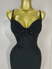 Black beaded dress on a mannequin against a plain background
