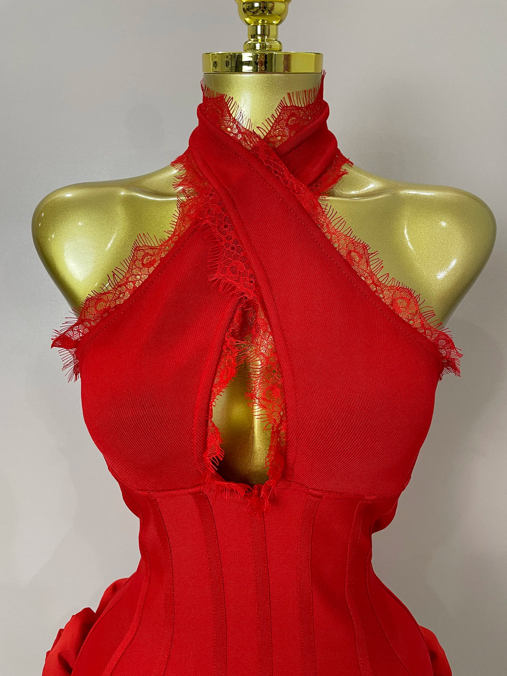 Red lace dress on a gold mannequin against a plain background