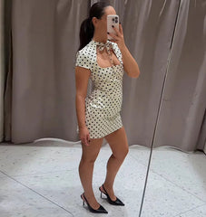 Woman taking a mirror selfie wearing a polka dot dress in a neutral setting