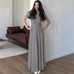 Woman in a long gray dress standing in a modern living room.