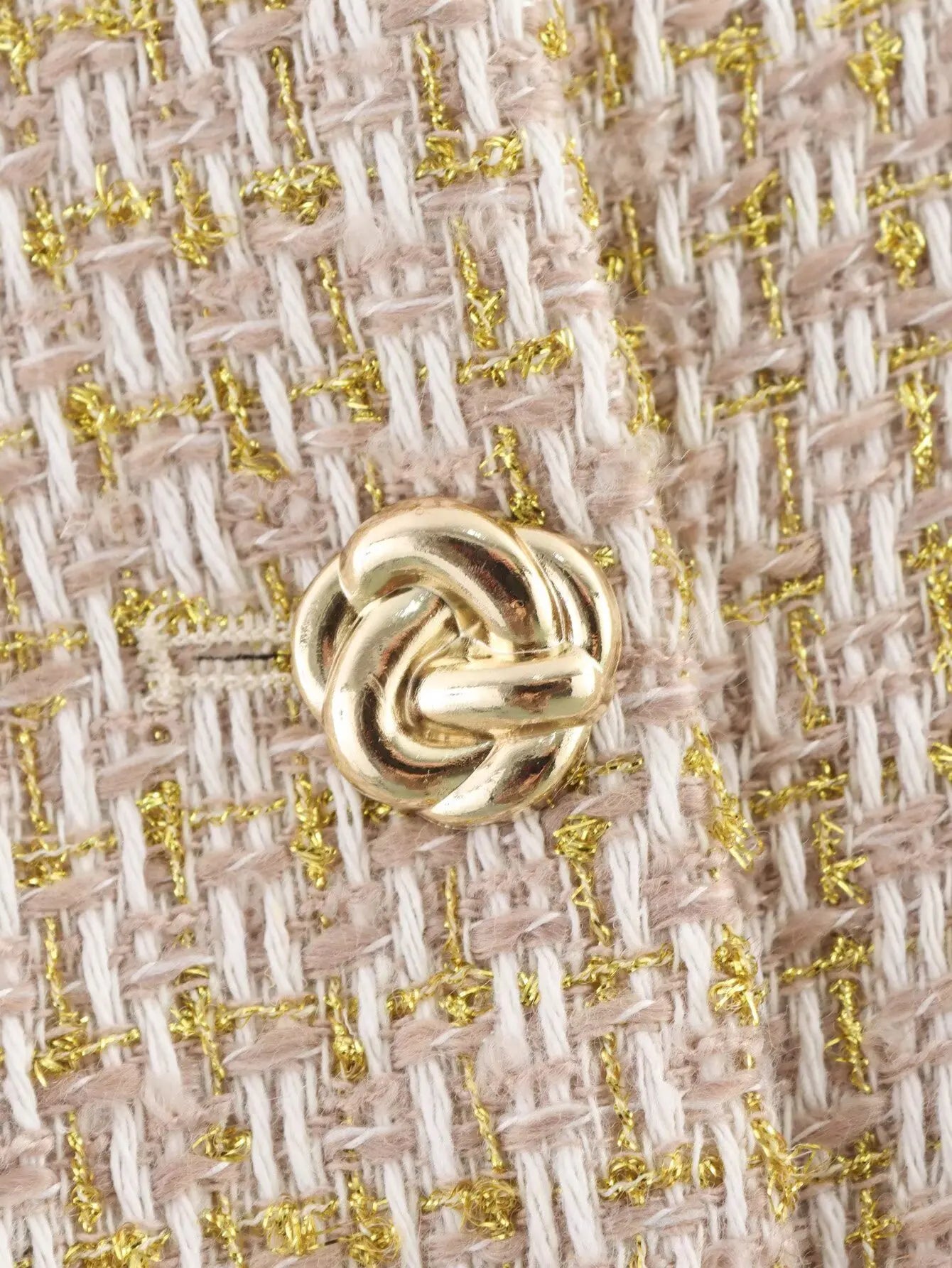 Close-up of a gold knot design on a textured fabric background