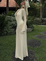 Woman in a long, sheer white dress standing in a garden setting.