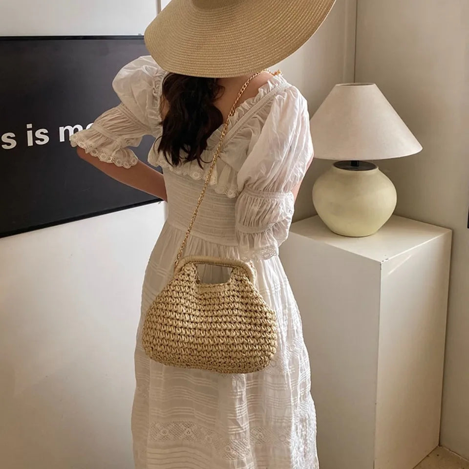 Woman in a white dress holding a straw bag indoors
