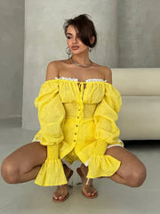 Woman wearing a yellow off-shoulder outfit posing in a minimalistic setting.