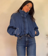 Person wearing a blue denim jacket and jeans against a plain background