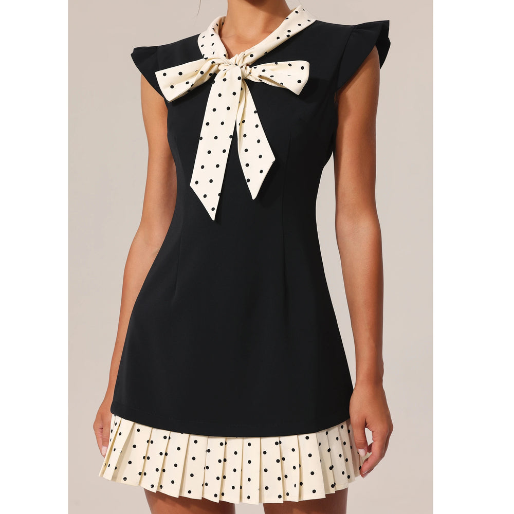 Black sleeveless top with a polka dot bow and matching skirt on a neutral background