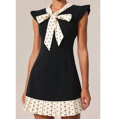 Black sleeveless top with a polka dot bow and matching skirt on a neutral background