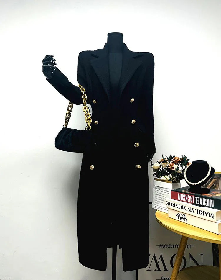 Black coat on a mannequin with a gold handbag against a white background