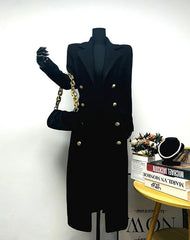 Black coat on a mannequin with a gold handbag against a white background