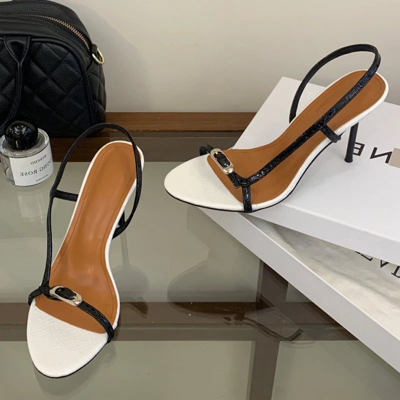 Pair of white and black thin strap buckle stiletto heels