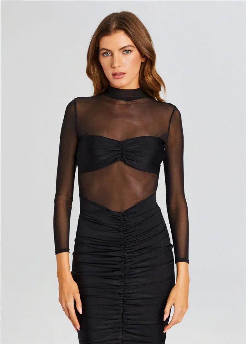 Woman wearing a black sheer long-sleeve top with a fitted skirt on a light gray background