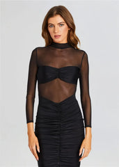 Woman wearing a black sheer long-sleeve top with a fitted skirt on a light gray background