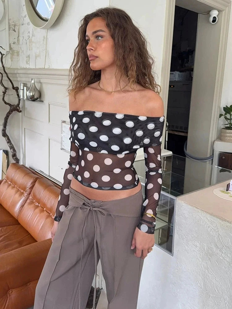 Woman wearing a polka dot top and gray pants in an indoor setting
