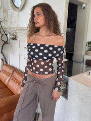 Woman wearing a polka dot top and gray pants in an indoor setting