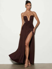 Woman wearing a brown strapless gown with a high slit on a white background