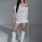 Woman wearing a white off-shoulder dress and white boots on a snowy background