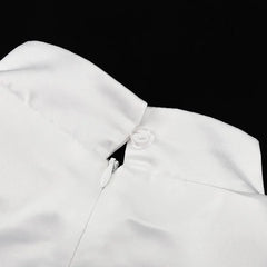 Close-up of a white garment with a collar and button on a black background
