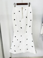 White skirt with black polka dots on a hanger against a white background