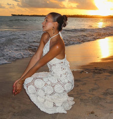 Woman in a white dress sitting on a beach at sunset