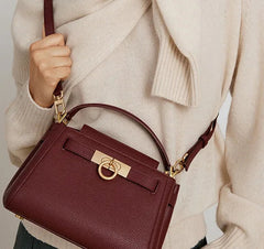 Close-up of burgundy structured top handle bag with detachable strap.