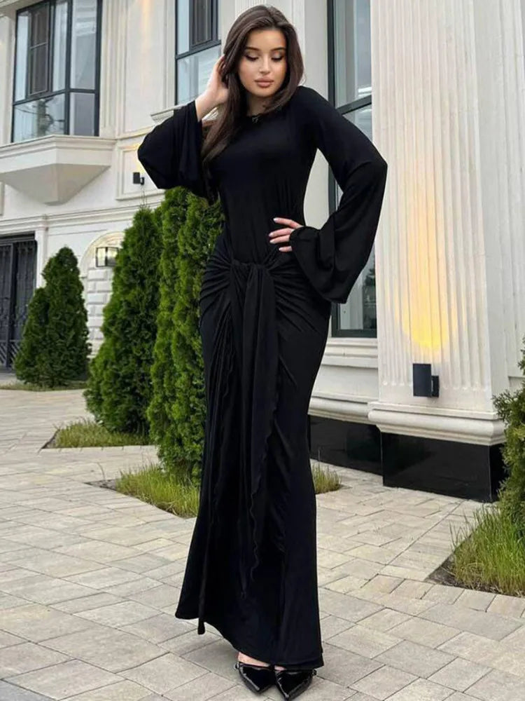 Woman wearing a black dress standing in front of a building.