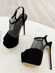 Black high-heeled shoes with rhinestone detailing on a white background