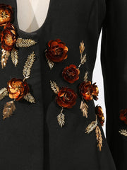 Black garment with gold and bronze floral embellishments on a white background