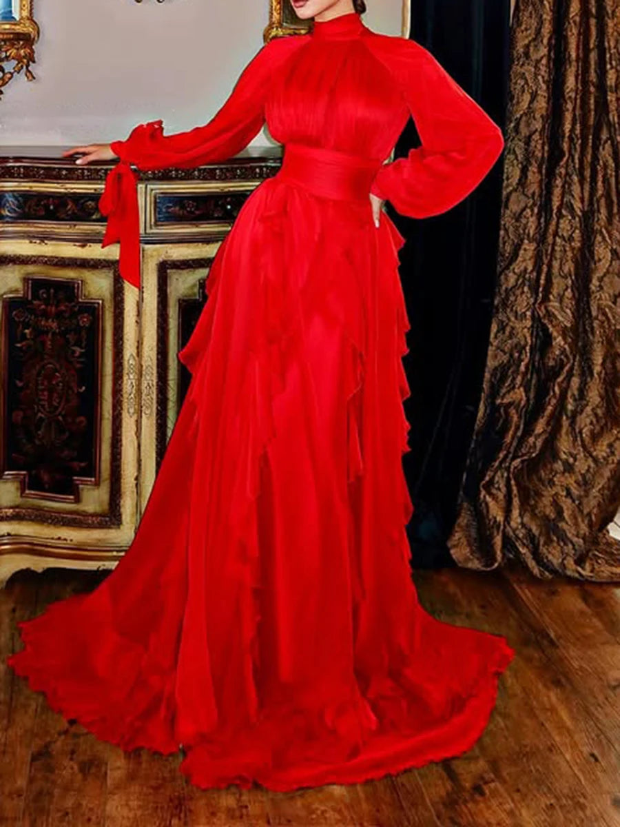 Red evening gown with long sleeves and a bow detail in an elegant room.
