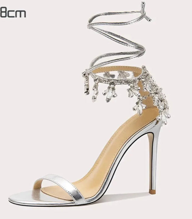 Silver high-heeled sandal with decorative straps on a white background