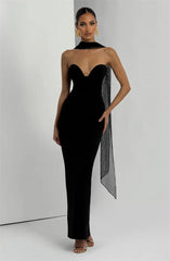 Woman wearing a black strapless gown with a sheer overlay on a white background