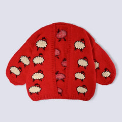 Red knitted hat with sheep pattern on a light gray background