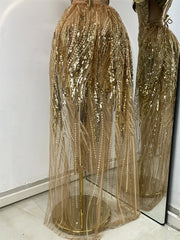 Gold sequin dress on a mannequin against a white wall.