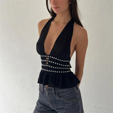 Black halter top with pearl details worn by a person against a white background