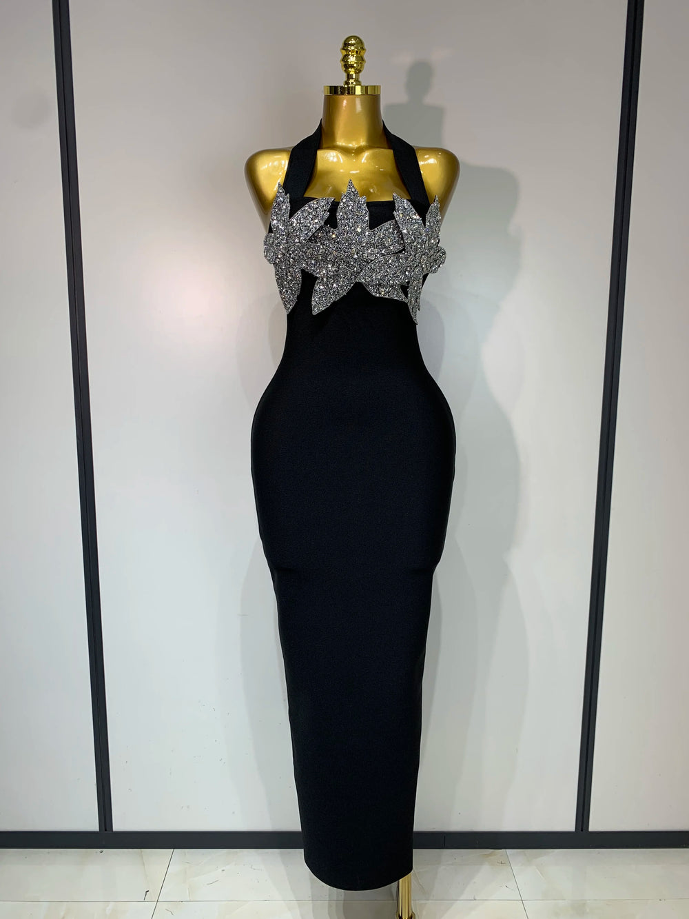 Black evening gown with silver embellishments on a mannequin against a white background