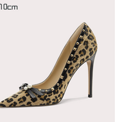 Leopard print high-heeled shoe with studded details on a light gray background
