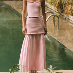 Person wearing a pink dress standing by a pool with greenery in the background