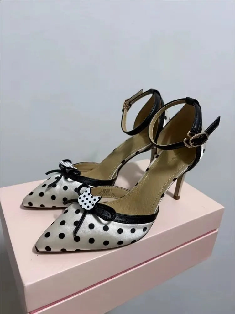 Black and white polka dot high-heeled shoes with bow details on a pink platform.