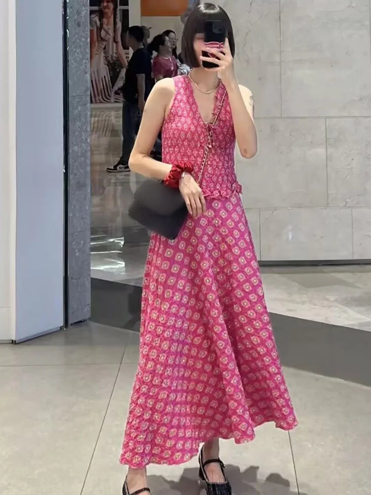 Woman in a pink floral dress holding a black clutch in an indoor setting.