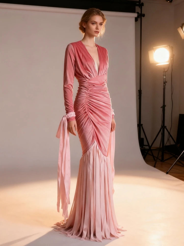 Model wearing a pink evening gown in a studio setting with lighting equipment.