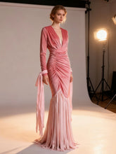 Model wearing a pink evening gown in a studio setting with lighting equipment.