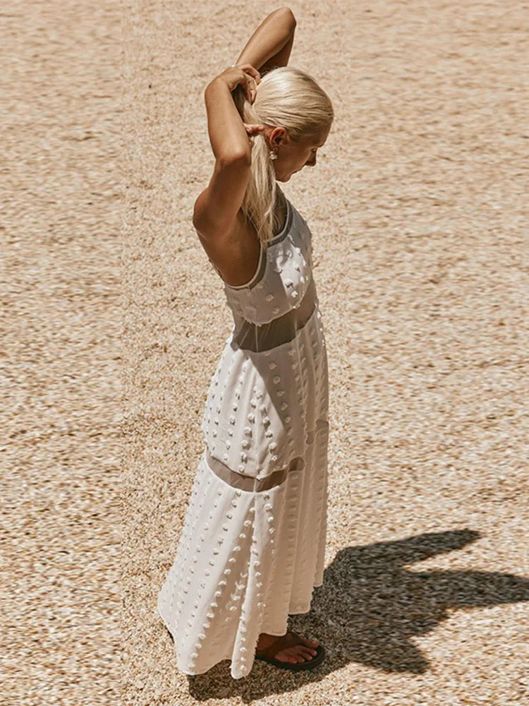Woman in a white dress standing on a textured beige surface