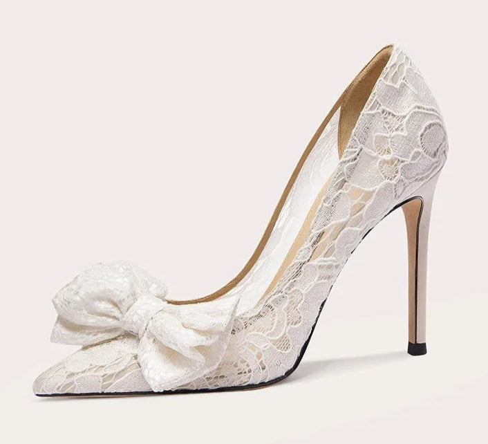 White lace high-heeled shoe with a bow on a light gray background
