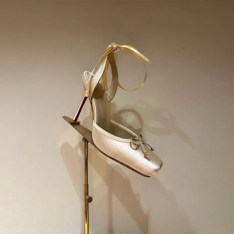 Gold high-heeled shoe on a stand against a beige background
