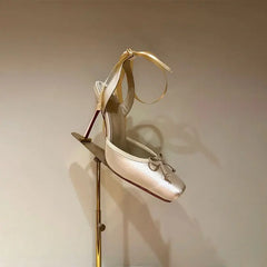 Gold high-heeled shoe on a stand against a beige background