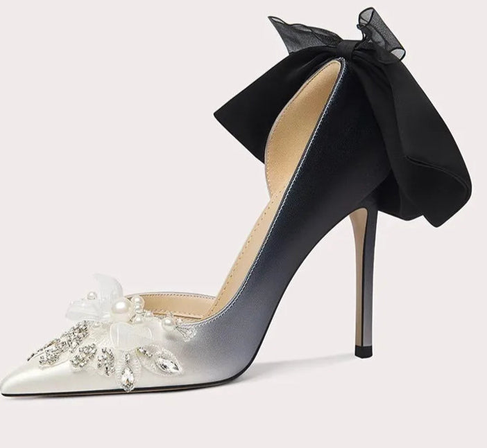 High-heeled shoe with a black bow and floral embellishments on a light gray background