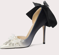High-heeled shoe with a black bow and floral embellishments on a light gray background