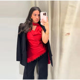 Woman taking a mirror selfie wearing a red top and black blazer.