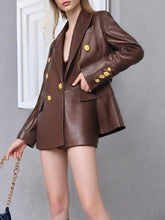 Brown leather suit with gold buttons worn by a person against a gray background